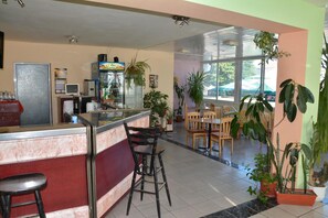A restaurant with a bar area, seating, and potted plants. - Hotel Wesso (Kavarna)