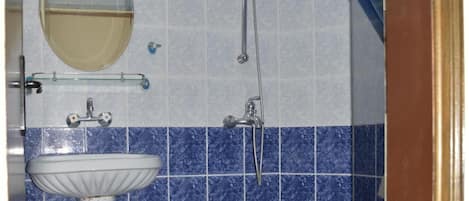 A bathroom with a pedestal sink, a toilet, and a shower area.