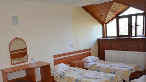 Una habitación con dos camas individuales, un escritorio de madera con un espejo y un radiador.