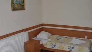 Una habitación con dos camas individuales, una mesita de noche de madera, un radiador y un cuadro en la pared.