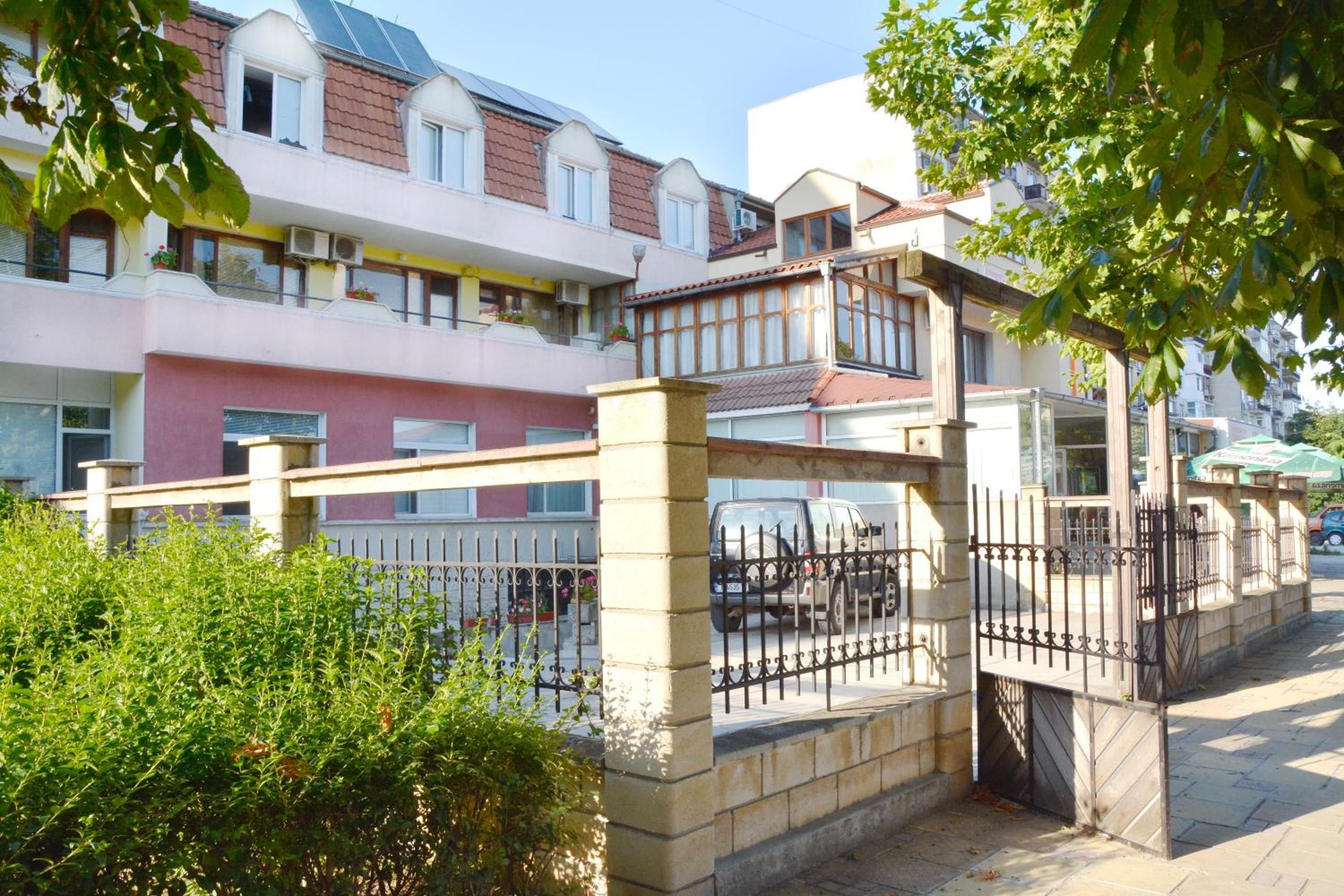 A residential building with multiple balconies, a gated entrance, and a paved pathway.