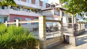 Un edificio residencial con varios balcones, entrada protegida por un portón y un camino pavimentado.