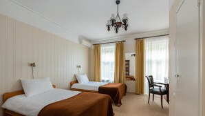 Une chambre d’hôtel avec deux lits, un bureau, une chaise et un lustre.