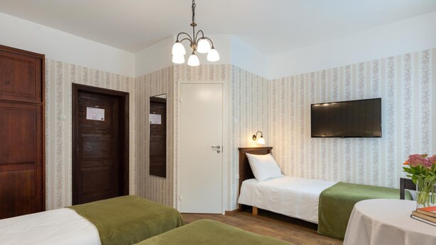 Une chambre d’hôtel avec deux lits, une télévision, un bureau et un lustre.