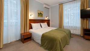 Une chambre d’hôtel avec un lit, des lampes de chevet, une télévision et un tableau au mur.