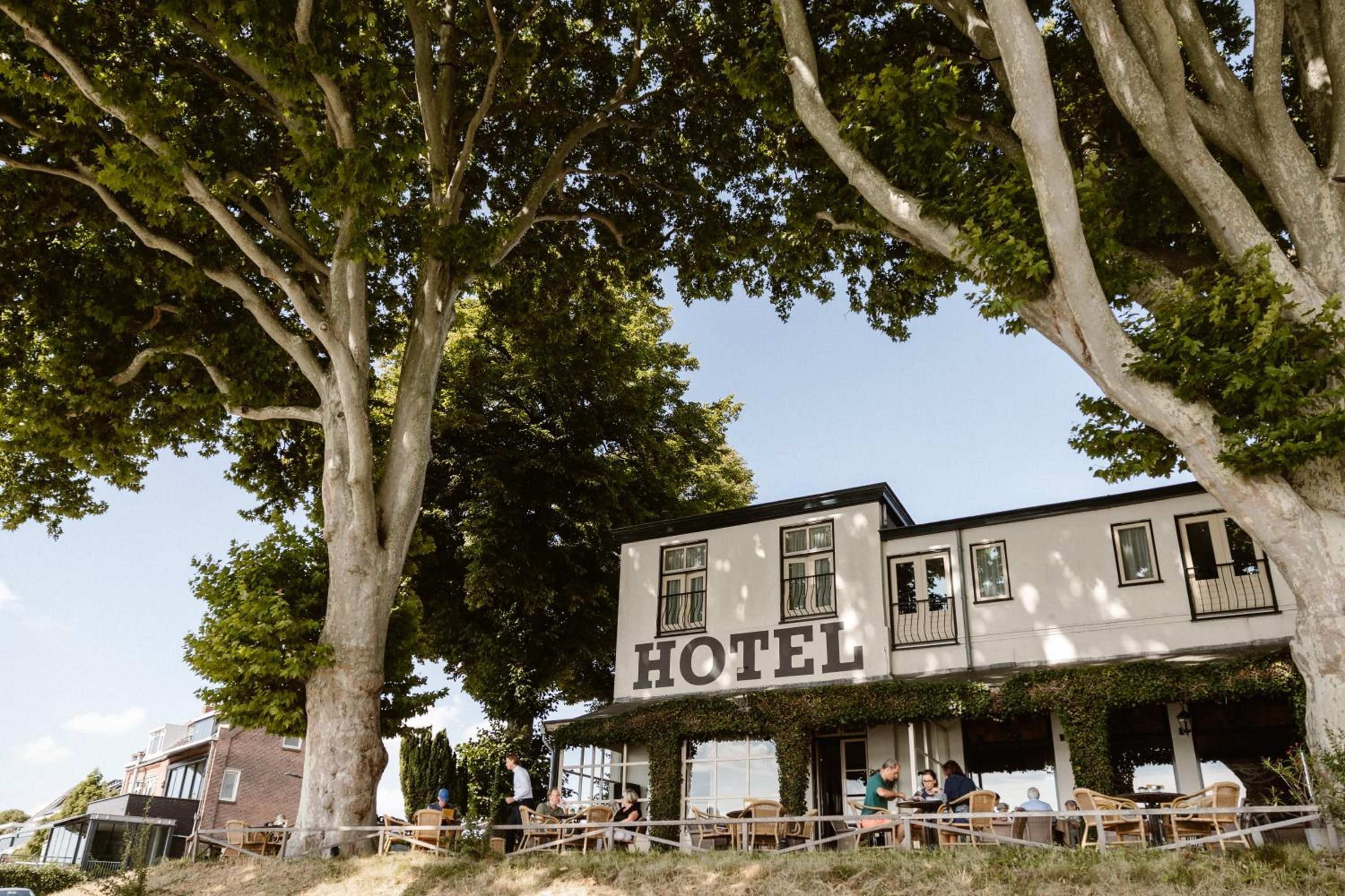 Een hotel met een wit gevel, veel ramen en terrasjes.