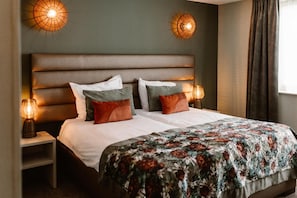 Quarto de hotel com uma cama grande, duas luminárias de cabeceira e um encosto de cama.