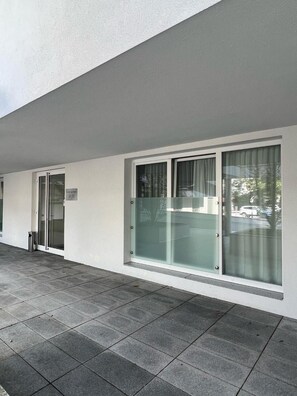 A building exterior with a flat roof, large windows with frosted glass, and a paved entrance area. - Hotel Gv Sser Brv U (Wels)