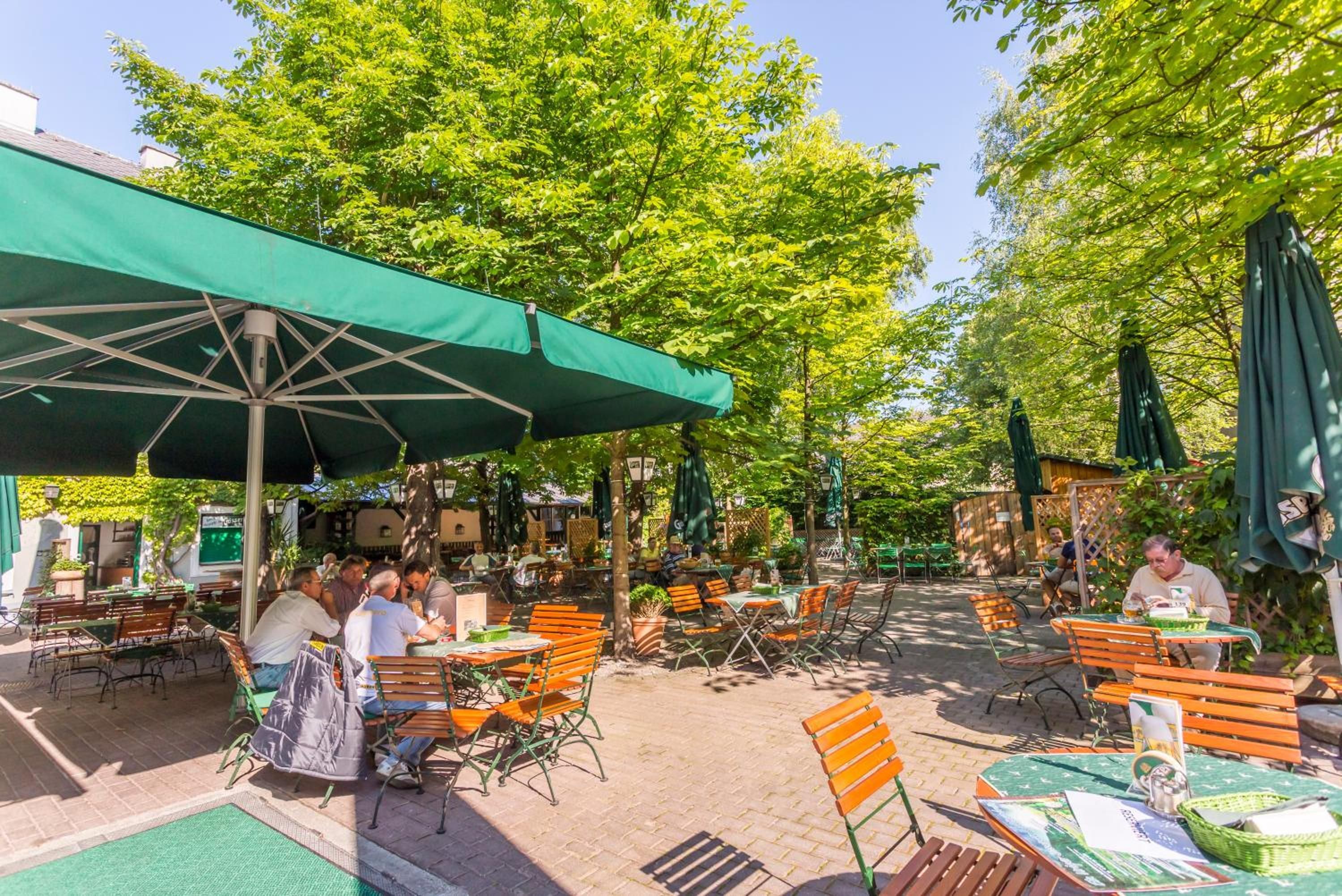 An outdoor café with tables and chairs, surrounded by trees.