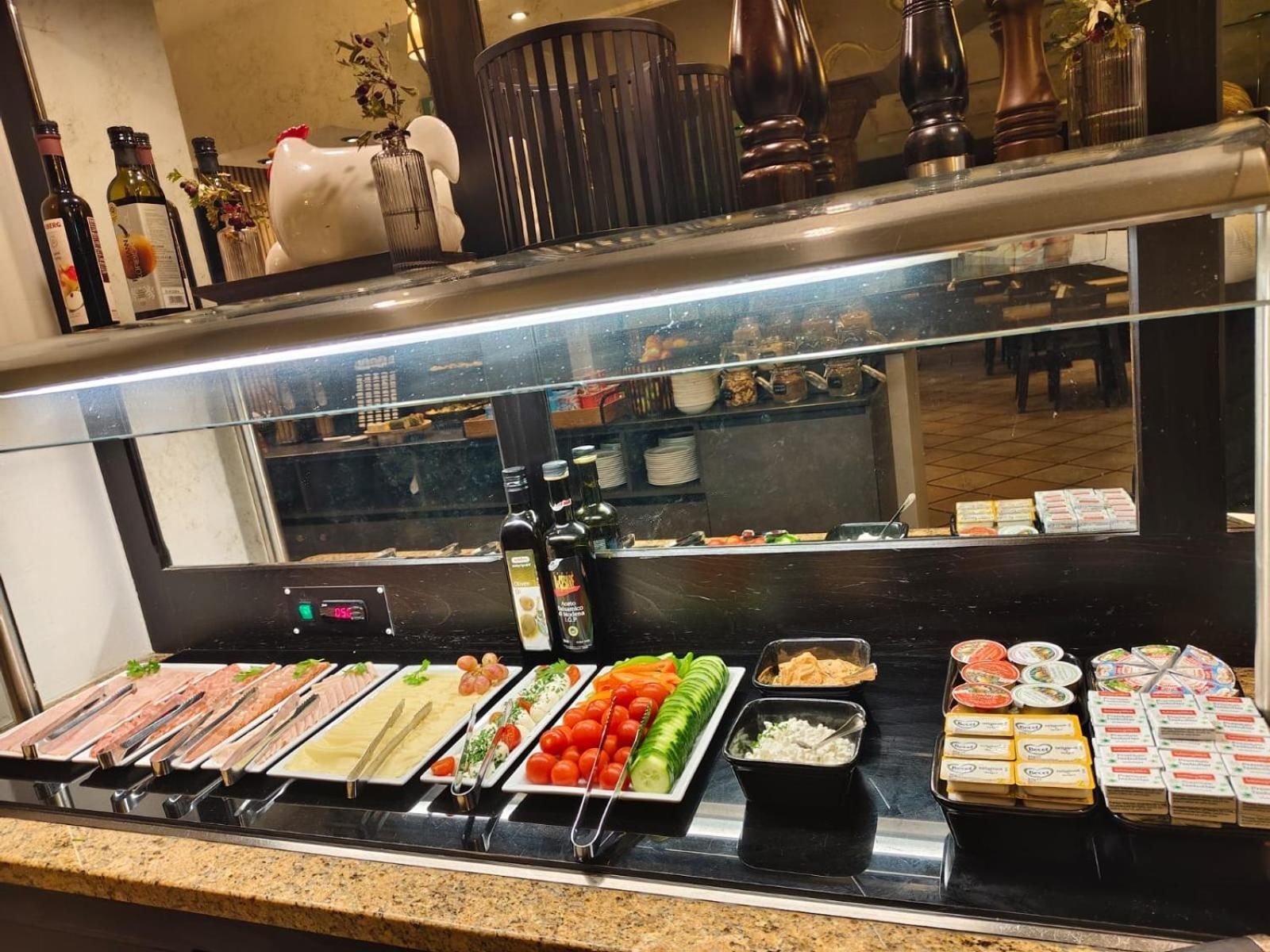 A buffet counter with various food items and condiments.