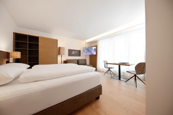 A hotel room with a large bed, a desk with a chair, a television, and a window with curtains. - Hotel Gv Sser Brv U (Wels)