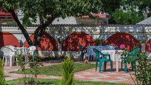 Zona exterior amb taules i cadires, envoltada d'un jardí amb un camí de maons.