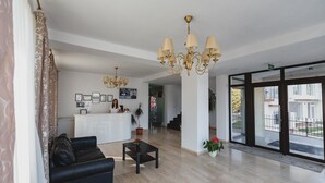 Un vestíbul d'hotel amb una taquilla de recepció, un sofà de pell negra, una taula de café i un penjador.