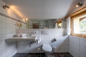 A modern bathroom with a white sink, toilet, and mirror. - Hotel Alpina (Schiers)