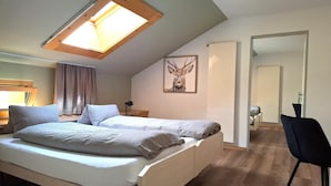 Une chambre avec un puits de lumière, un lit avec des oreillers, un bureau, une chaise et un tableau encadré au mur.