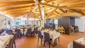 Un restaurant doté d’un haut plafond en bois et de nombreuses tables dressées pour accueillir les clients.