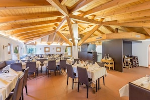 A restaurant with a high wooden ceiling and multiple dining tables set for guests. - Hotel Alpina (Schiers)