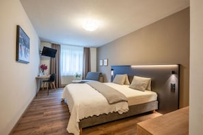 A hotel room with a bed, bedside table, and a desk with a chair. - Hotel Alpina (Schiers)