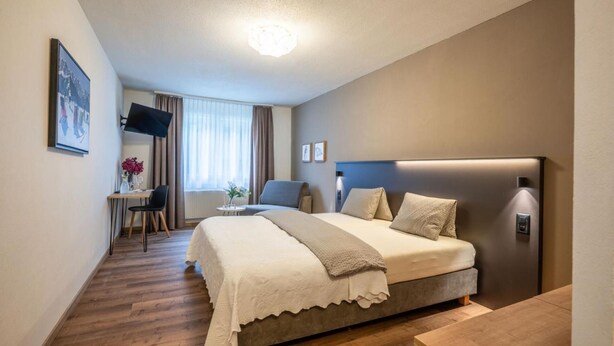 Une chambre d’hôtel comprenant un lit, une table de chevet et un bureau avec une chaise.