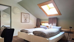 Une chambre avec une lucarne, un lit, une chaise et une petite table.