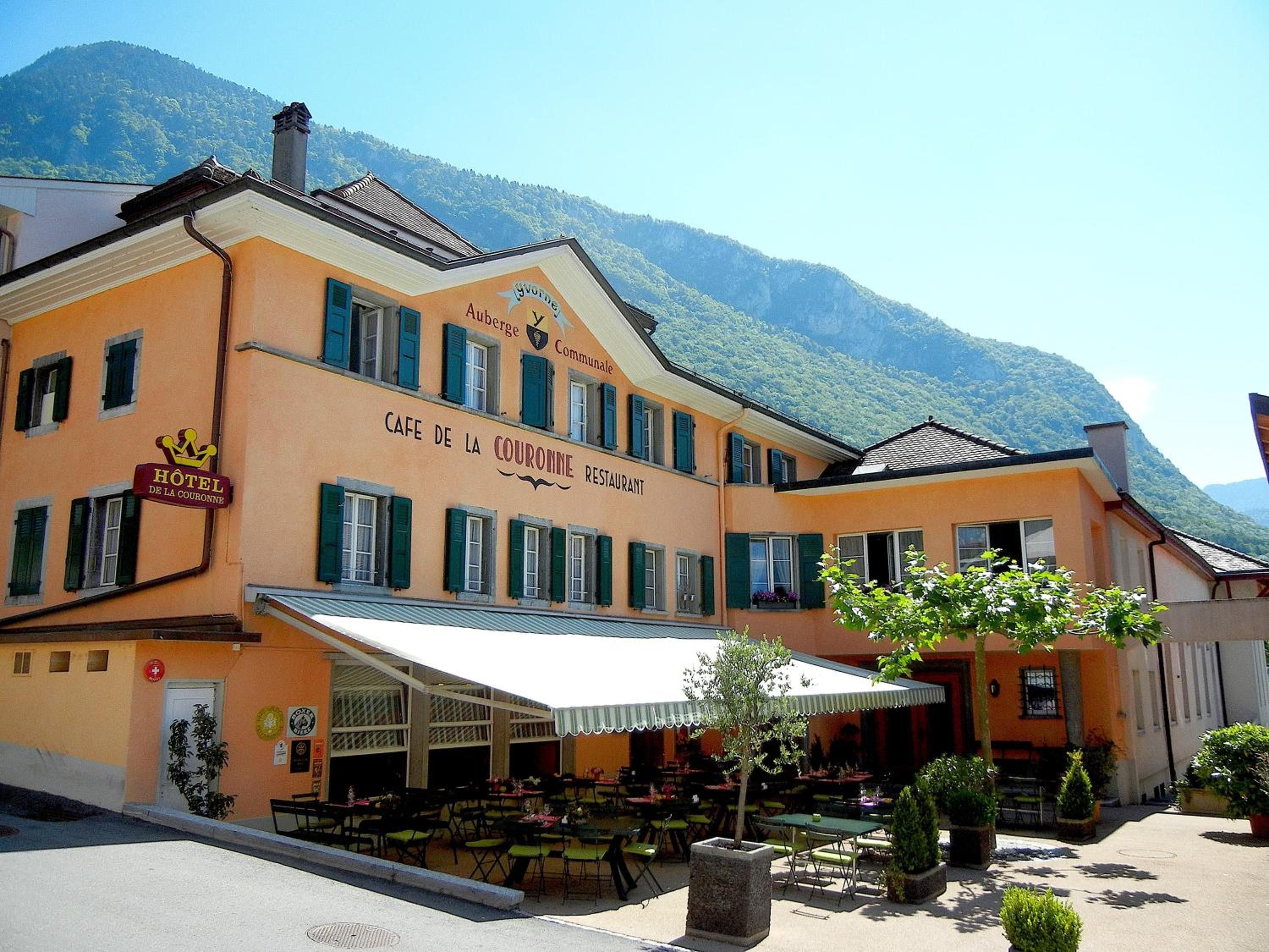 Un hôtel doté d’une terrasse, avec une vue sur les montagnes et une signalétique indiquant qu’il s’agit d’un restaurant.