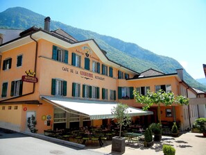 Un hôtel doté d’une terrasse, avec une vue sur les montagnes et une signalétique indiquant qu’il s’agit d’un restaurant.