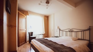 Ein Hotelzimmer mit Bett, Schreibtisch, Stuhl und einem fenster mit Vorhängen.
