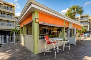 A small outdoor bar with a green and orange awning, white chairs, and a brick-paved patio. - Waterfront, 8 Min to TPA & 12 Min Raymond James (Tampa)