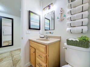 A bathroom with a wooden vanity, a sink, two mirrors, a towel rack with white towels, and a small plant on the toilet. - Waterfront, 8 Min to TPA & 12 Min Raymond James (Tampa)
