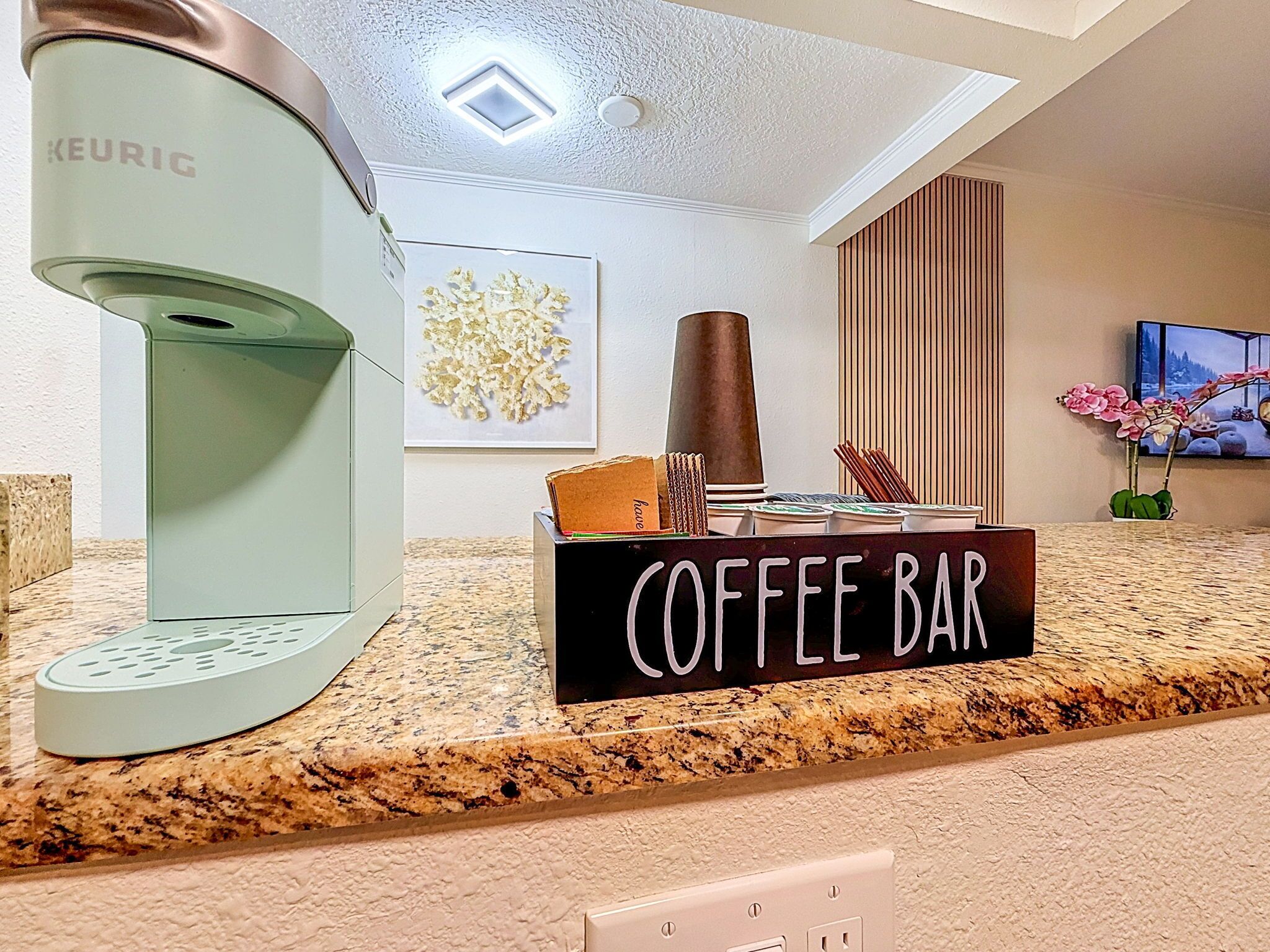 Ein Cafébereich mit einer Keurig-Kaffeemaschine, einer Kaffeestation und einem Schild mit der Aufschrift 'COFFEE BAR'.