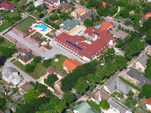 An aerial view of a residential area with a large building featuring a swimming pool and solar panels.