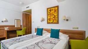 Una habitación de hotel con cama, escritorio, silla y un cuadro en la pared.