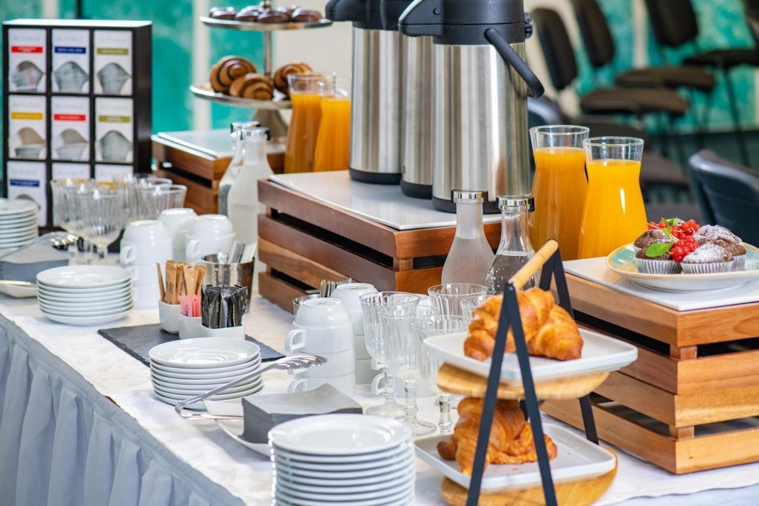 A breakfast buffet with various food items, a coffee maker, and a juice dispenser.