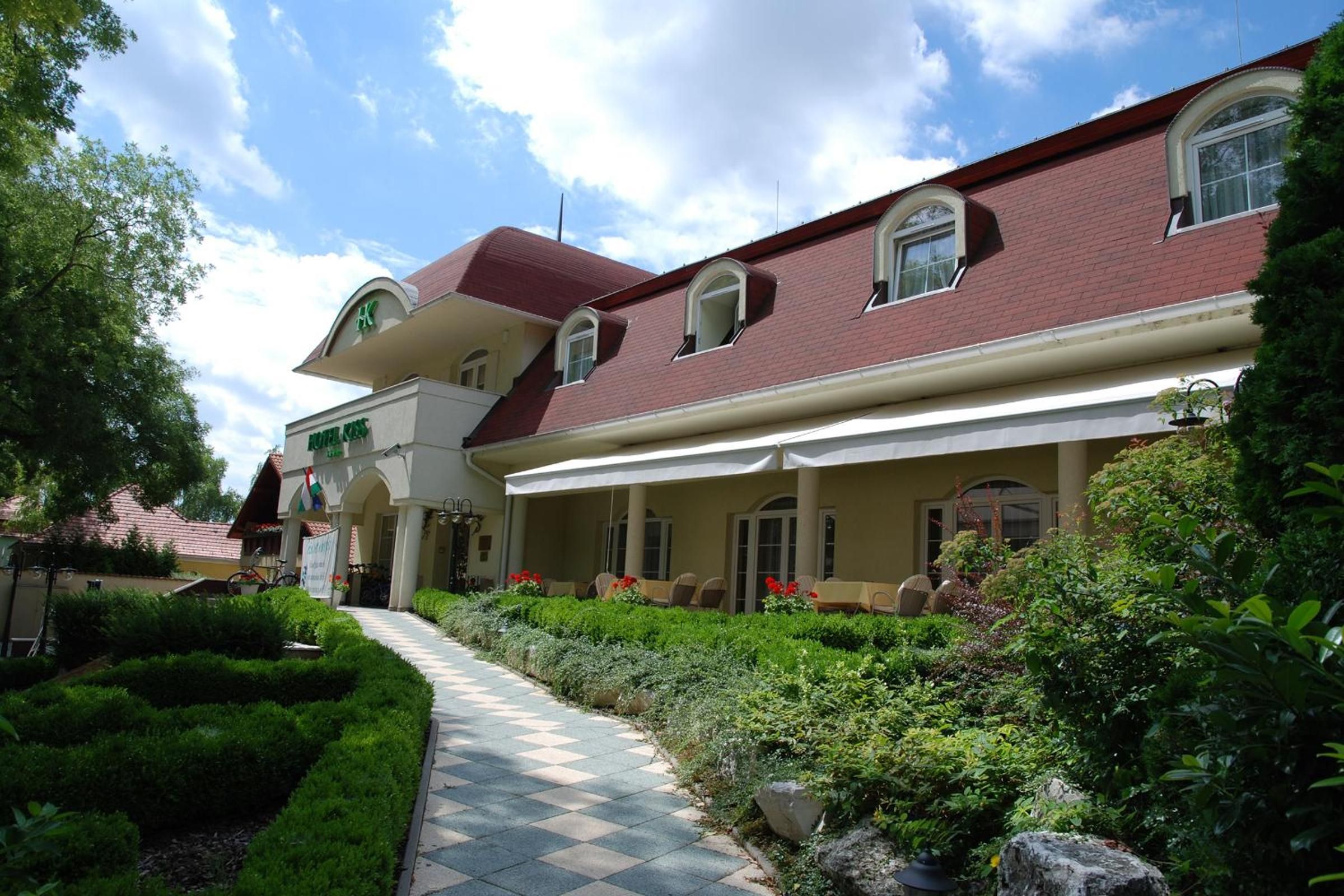 Un hotel con un patio central, una zona de estar cubierta al aire libre y un jardín bien cuidado.