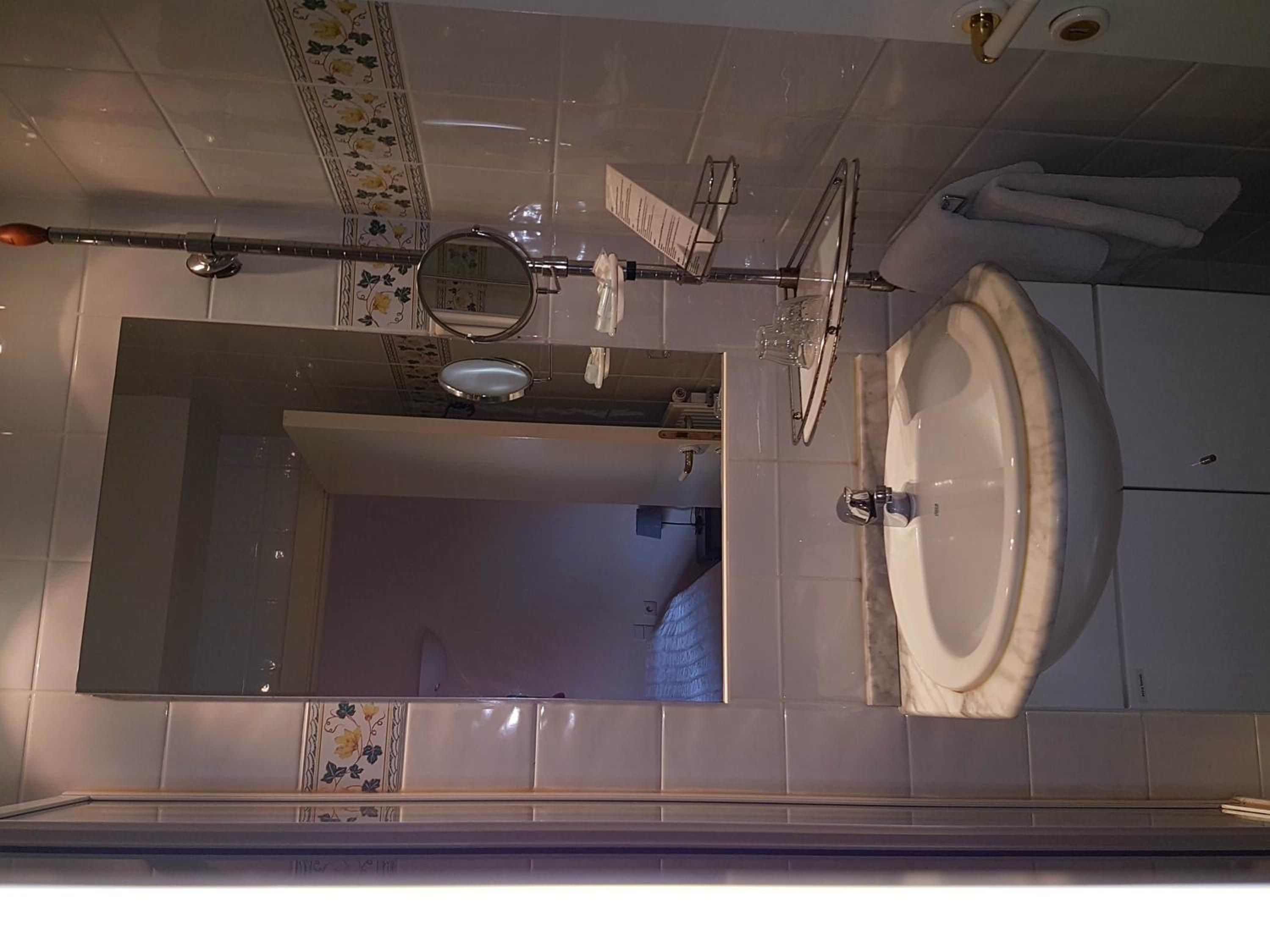 Een badkamer met een grote spiegel, een wastafel en een handdoekrek.