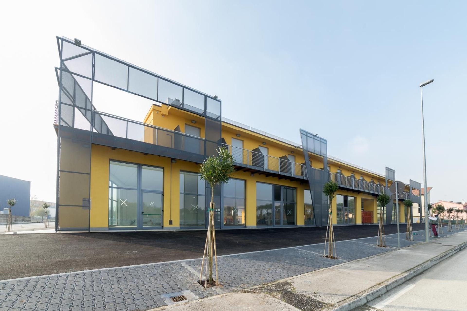 A modern building with a yellow facade, large windows, and a flat roof.