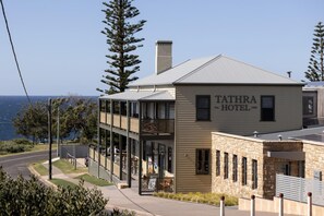 A two-story building with a sign reading 'TATHRA HOTEL' and a view of the ocean in the background. - Tathra Hotel Motel (Tathra)