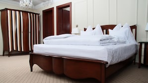 Habitación de hotel con una cama grande, dos puertas, una araña y suelo de baldosas.