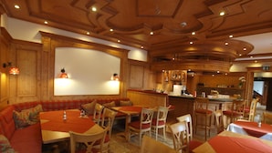 Un restaurante con decoración de madera, varias zonas de estar que incluyen cabinas y mesas, y un área de bar.