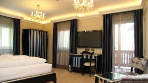 Una habitación de hotel con cama, escritorio, silla, televisor y candelabro.