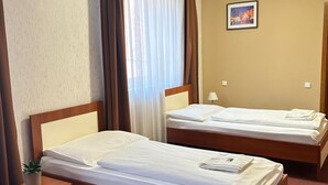 Habitación de hotel con dos camas, una mesita de noche, una lámpara y un cuadro en la pared.