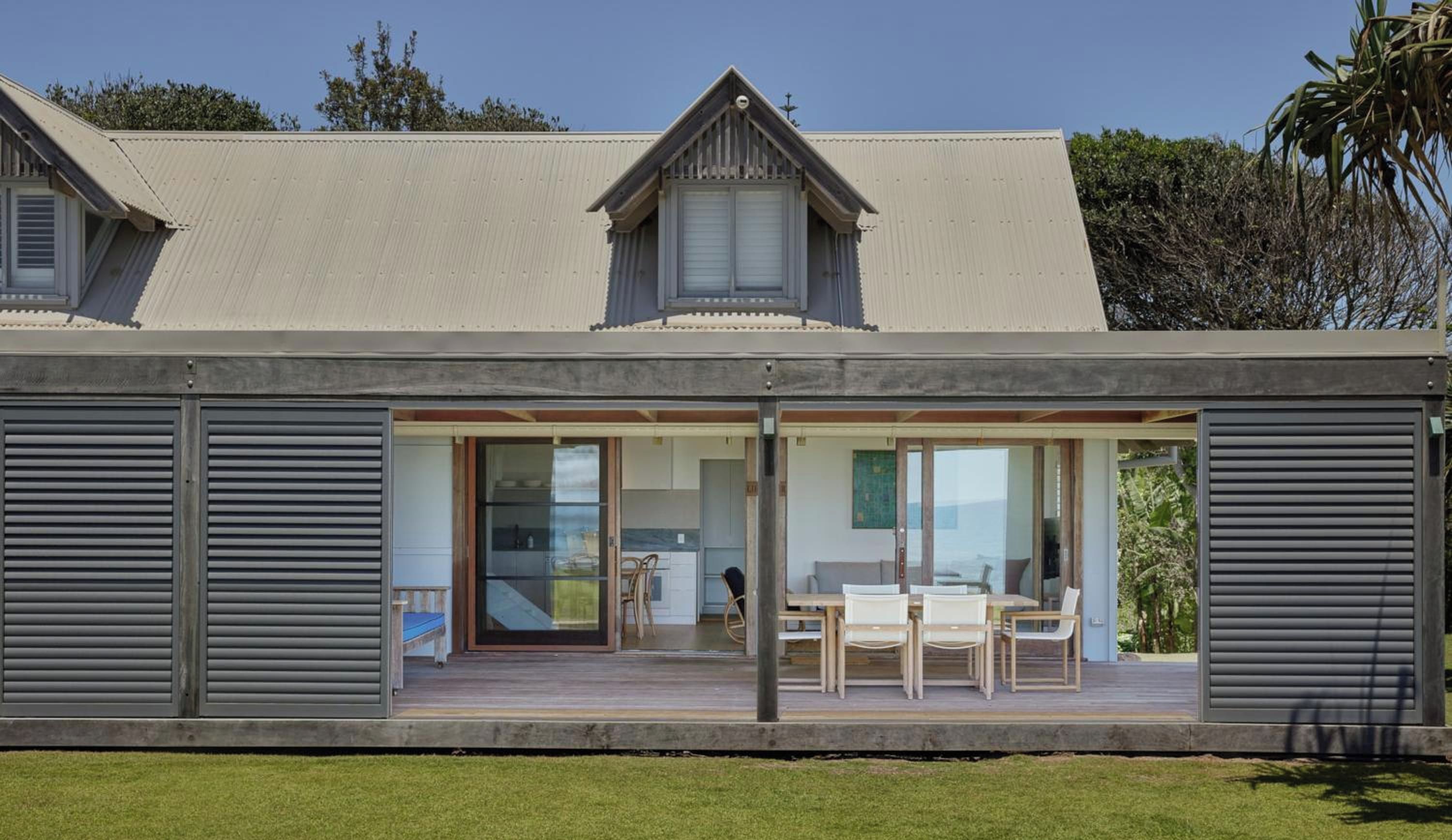A modern house with a covered porch, large sliding glass doors, and a dining area.
