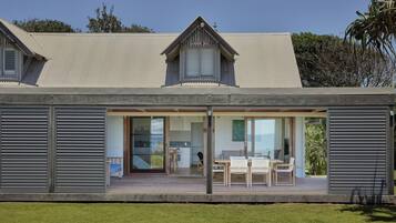 A modern house with a covered porch, large sliding glass doors, and a dining area.