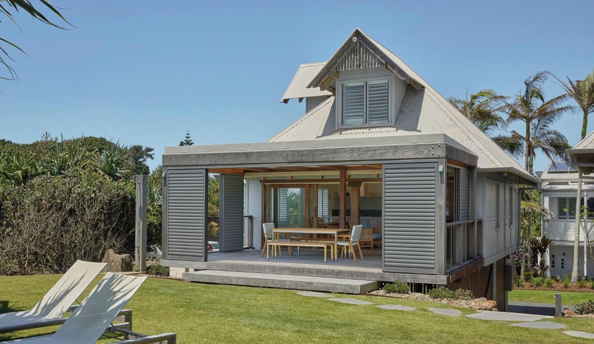 A modern house with a covered patio, a dining area, and a view of the surrounding landscape.