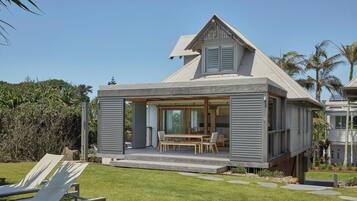 A modern house with a covered patio, a dining area, and a view of the surrounding landscape.