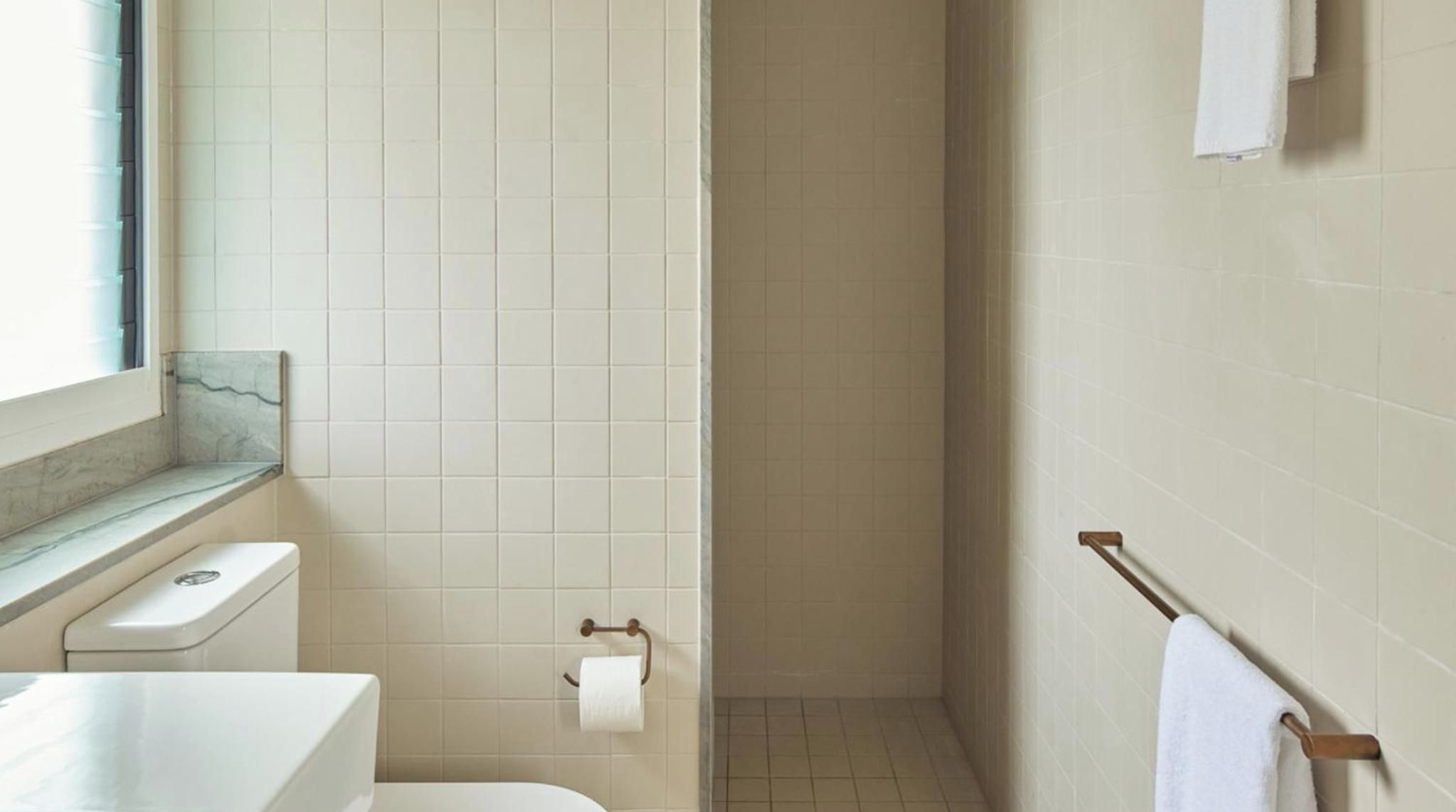 A bathroom with a toilet, a towel rack, and a shower area.