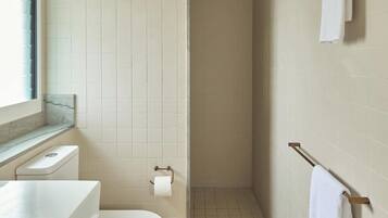 A bathroom with a toilet, a towel rack, and a shower area.
