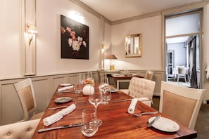 A dining room with a wooden table set for six, surrounded by chairs, a vase with flowers, and a painting on the wall. - Boutique Hotel U Solnv Brv Ny (České Budějovice)
