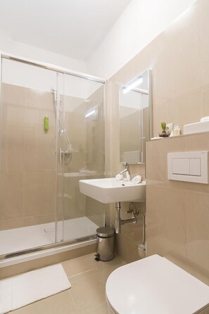 A modern bathroom with a glass-enclosed shower, a white sink, and a toilet. - Boutique Hotel U Solnv Brv Ny (České Budějovice)