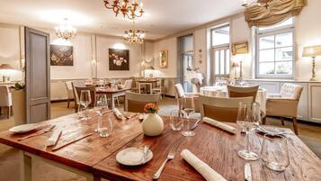 A dining area with multiple tables, chairs, and chandeliers.